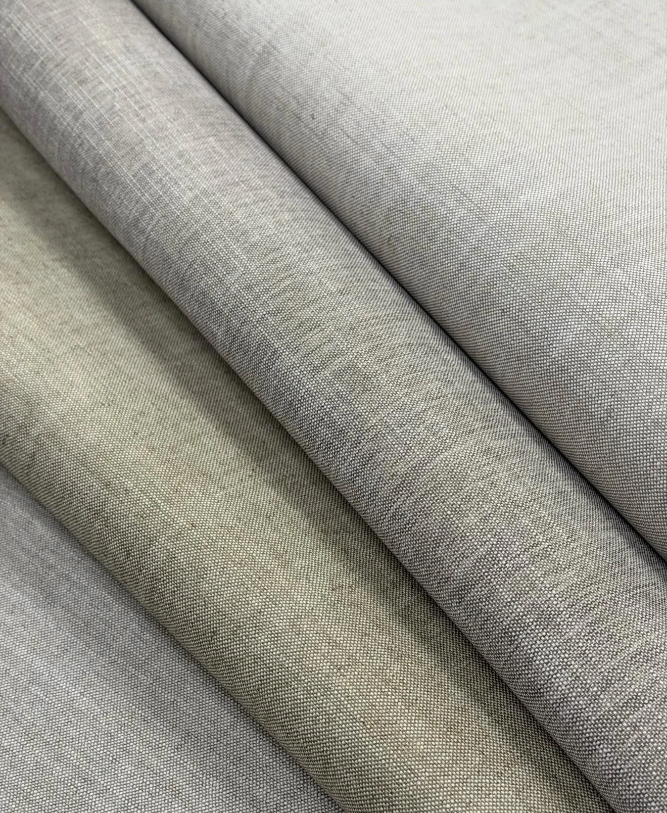 Folded linen samples in pale grey and warm beige showing their fine textile weave