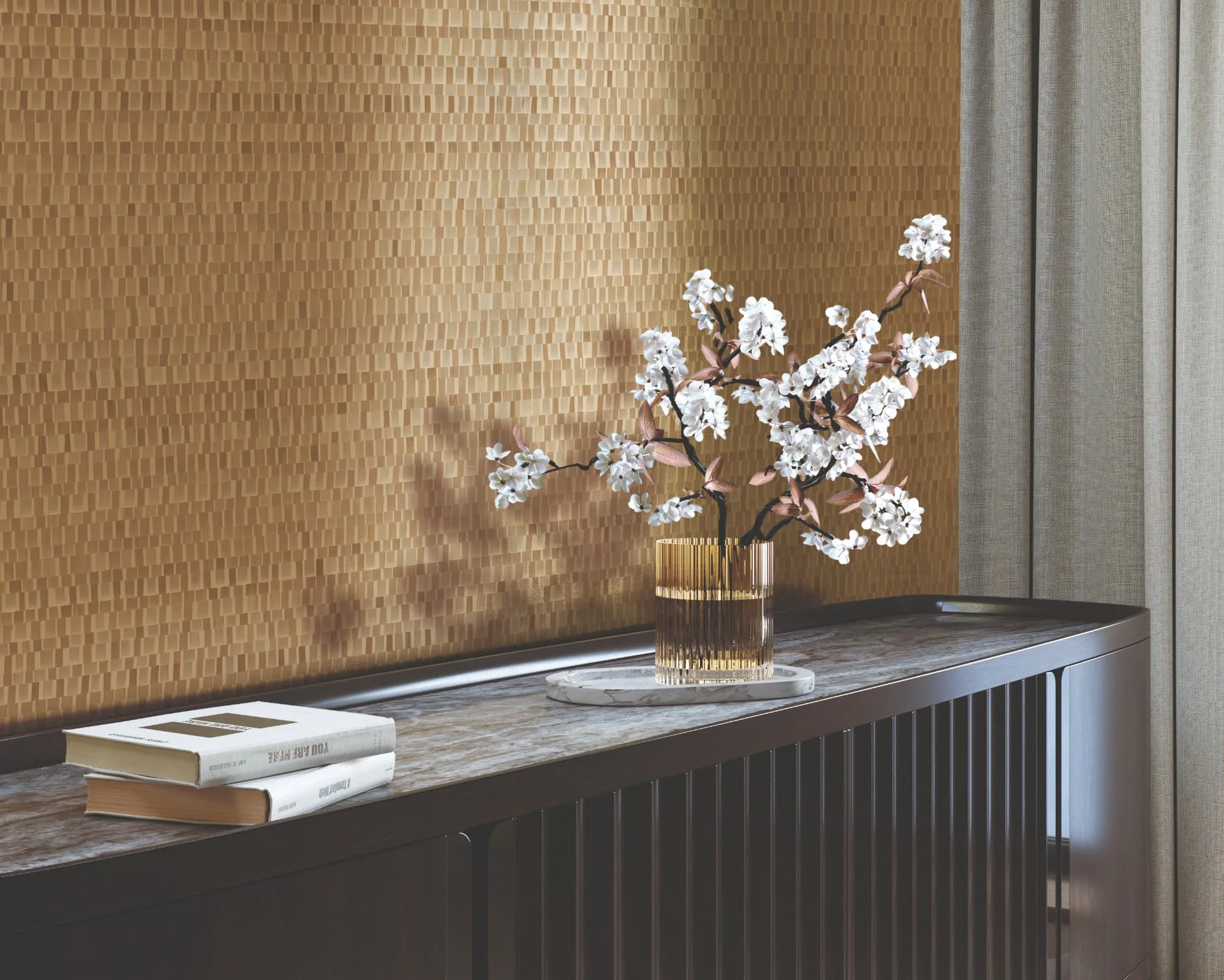 Warm gold textured wallcovering above a dark fluted sideboard with blossom in a glass vase