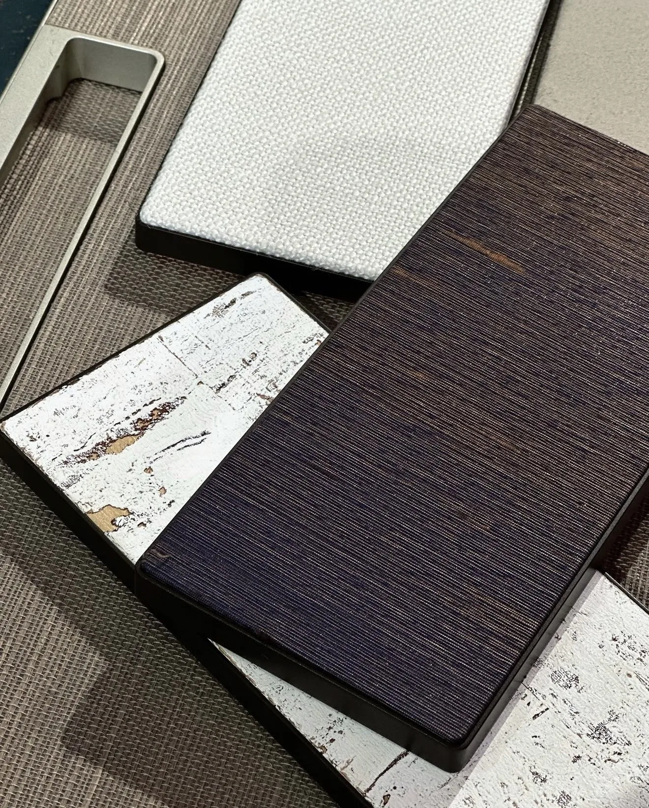 A curated selection of John Mark Naturals wallcovering samples laid together, showing contrasting textures, weaves and natural surfaces