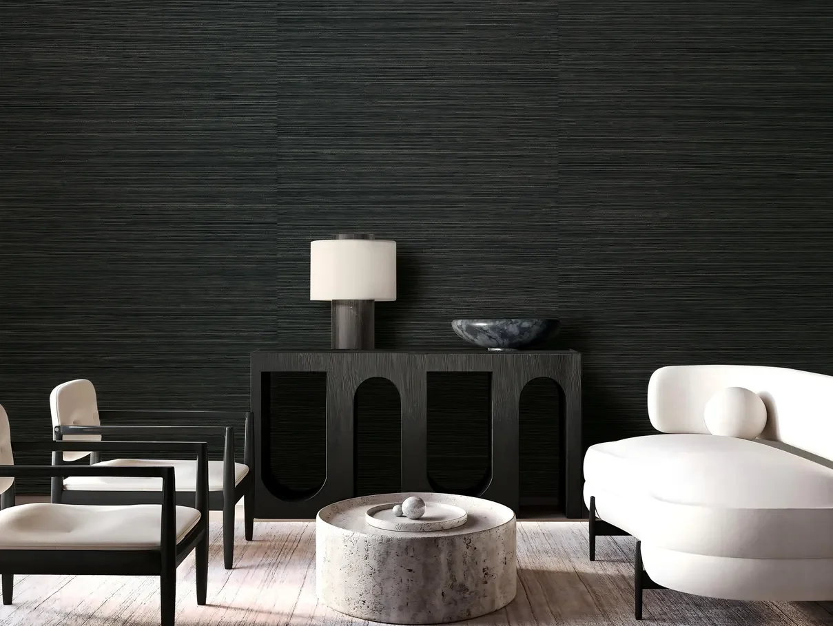 Living space with a deep charcoal sisal wallcovering behind a black arched console, a cream table lamp, a travertine coffee table and ivory seating