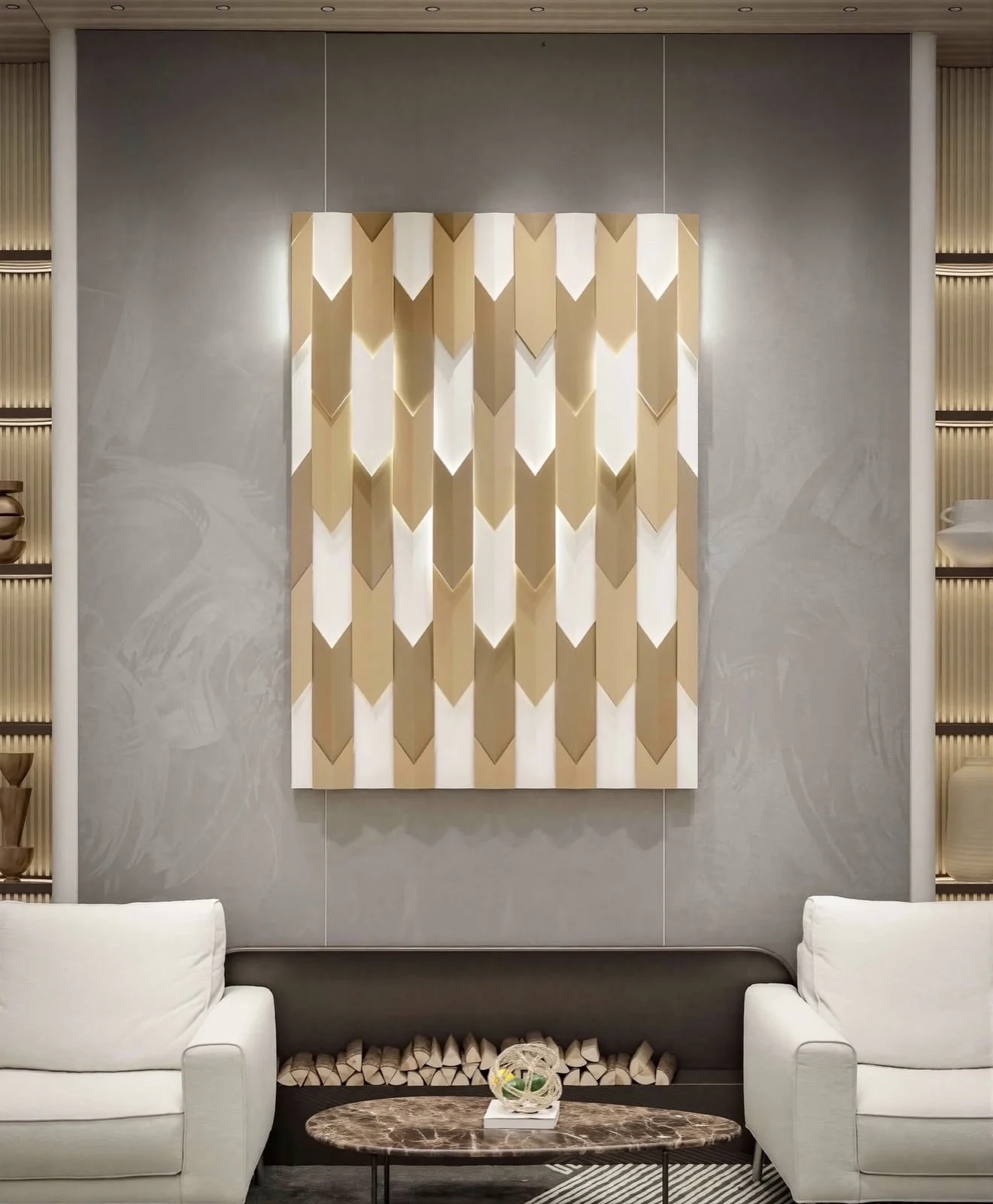 Lounge with a soft grey suede wallcovering behind a sculptural white and gold chevron wall panel, two white armchairs and an oval marble coffee table