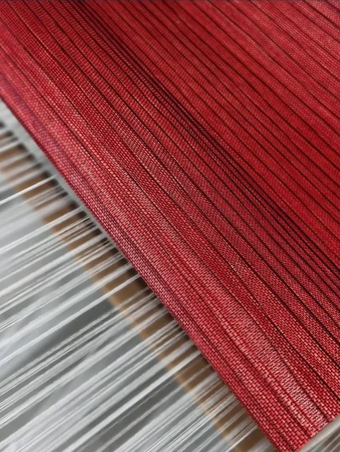 Close-up of a deep red textural natural wallcovering with fine lengthwise ribs