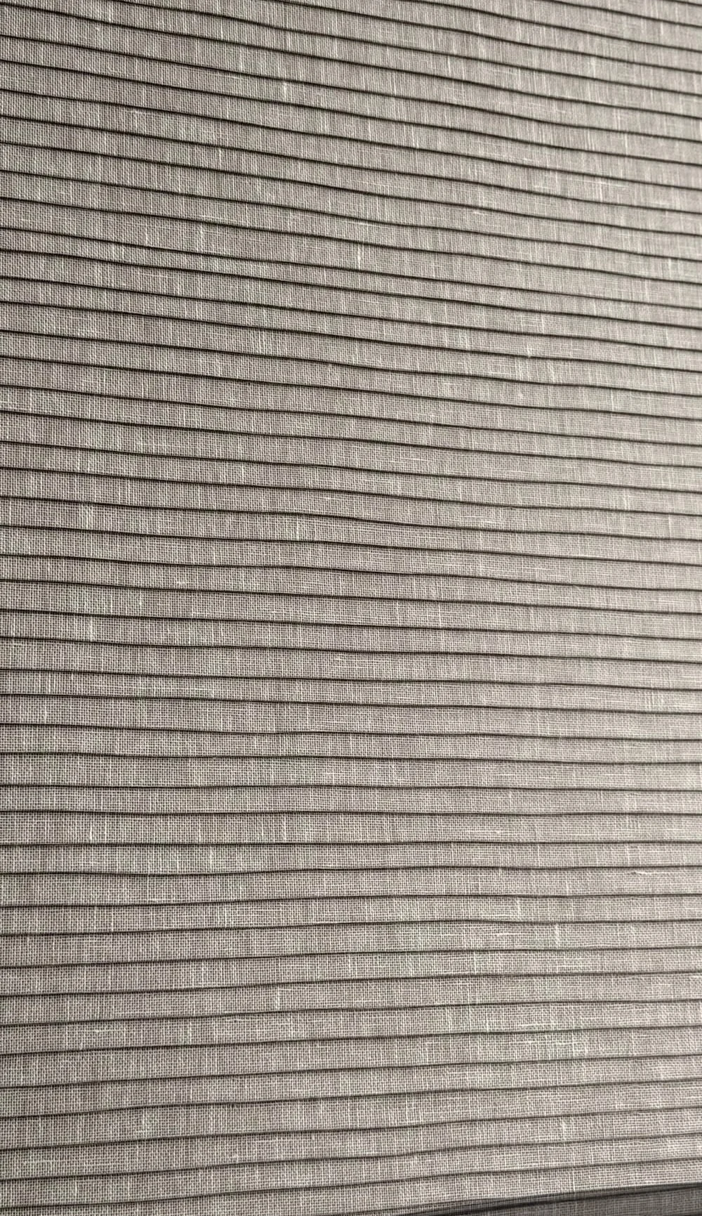 Close-up of a linen wallcovering with a fine horizontal weave catching raking light