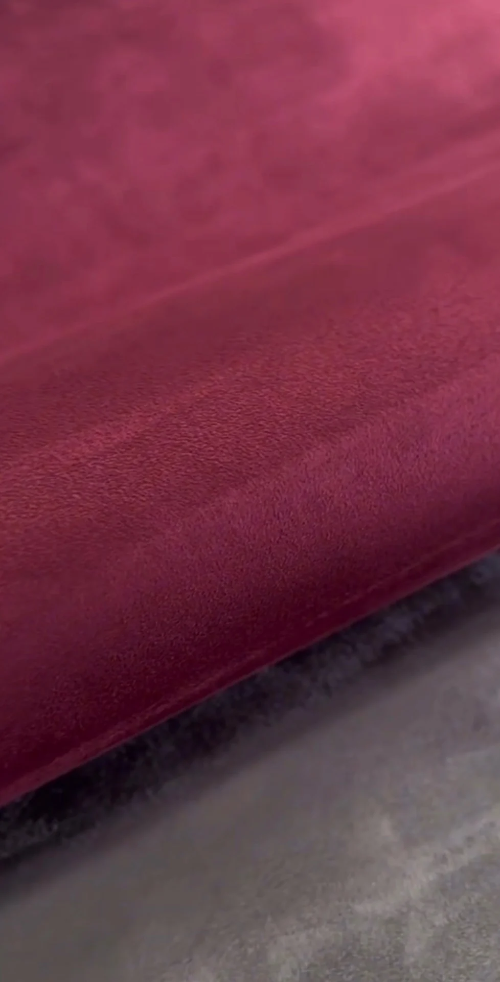 Close-up of a rich red suede wallcovering folded over a deep grey surface, showing its soft matte nap